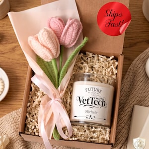 May include: A gift box containing two crocheted tulips in light and dark pink with green stems, wrapped in light pink paper with a ribbon, and a glass candle with a white label reading Future VetTech and the name Michele in black text.