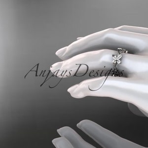 Puede incluir: Un delicado anillo de plata con una fila de peque&ntilde;os diamantes brillantes engastados en forma de mariposas.