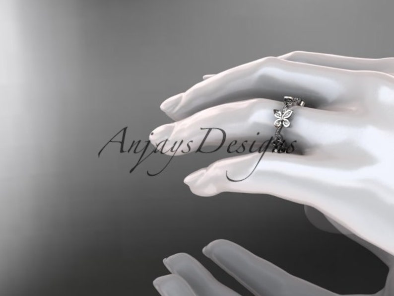 Puede incluir: Un delicado anillo de plata con una fila de peque&ntilde;os diamantes brillantes engastados en forma de mariposas.