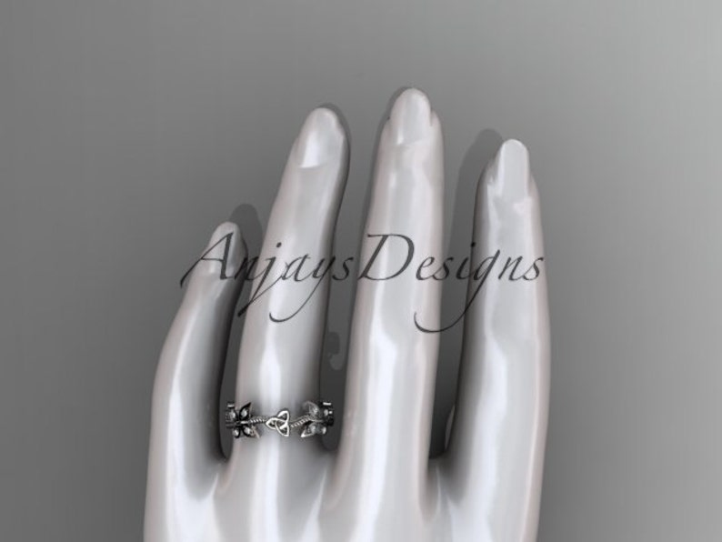 Puede incluir: Un anillo de plata con un dise&ntilde;o de nudo celta. El anillo est&aacute; en el dedo de una mano de maniqu&iacute;.