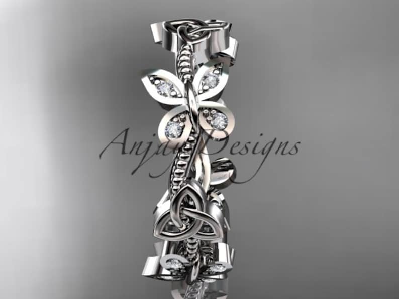Puede incluir: Un anillo de banda de plata con un dise&ntilde;o de nudo celta y peque&ntilde;os diamantes engastados en la banda. El anillo presenta un dise&ntilde;o floral con hojas y una mariposa.