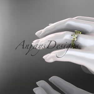 Puede incluir: Un anillo de banda de oro con un delicado dise&ntilde;o de mariposa engastado con peque&ntilde;os diamantes. El anillo est&aacute; en la mano de una modelo.