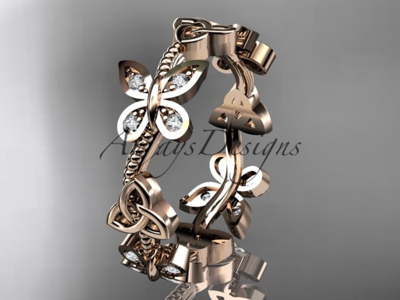Puede incluir: Un anillo de banda de oro rosa con un dise&ntilde;o de nudo celta y dos motivos de mariposa con peque&ntilde;os diamantes. El anillo es una pieza de joyer&iacute;a delicada e intrincada.