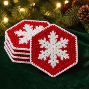 May include: A stack of hexagonal crochet coasters featuring a vibrant red background and a detailed white snowflake pattern in the center. Each coaster is finished with a white crocheted border, creating a cohesive set of winter-themed drink mats.