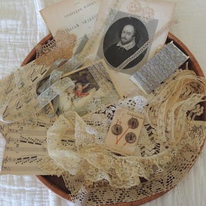 May include: A collection of cream and white lace trims, ribbons, and fabric scraps arranged with vintage paper ephemera, including a portrait of William Shakespeare, sheet music, and a small card with three brown buttons labeled Lady Washington.