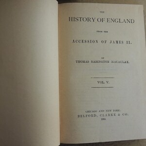 May include: Open book with text: "THE HISTORY OF ENGLAND FROM THE ACCESSION OF JAMES II. BY THOMAS BABINGTON MACAULAY. VOL V." Published by Belford, Clarke & Co. in Chicago and New York in 1884. The pages are off-white.