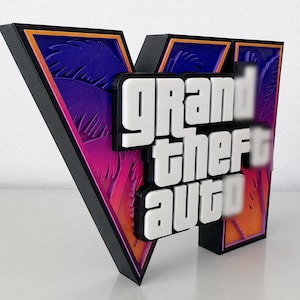 Puede incluir: Un letrero de pared tridimensional que presenta el logotipo de Grand Theft Auto en letras blancas sobre un marco negro en forma de V. El fondo muestra un degradado púrpura y naranja con un patrón de silueta de palmera, creando un efecto de capas.