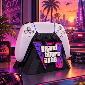 May include: A white and black video game controller resting on a black stand featuring a Grand Theft Auto VI logo with purple and pink palm tree graphics. The controller has standard buttons, joysticks, and a central touchpad in a gaming setup.