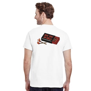 Könnte beinhalten: Weißes T-Shirt mit einer Grafik einer Streichholzschachtel und brennenden Streichhölzern. Die Streichholzschachtel ist schwarz mit dem Text "SEE YOU IN HELL". Die Streichhölzer sind rot und orange.