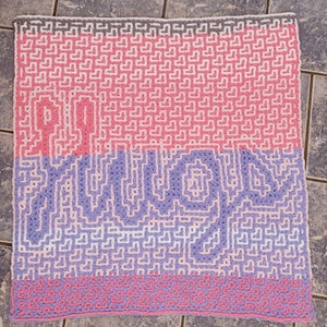 May include: A crocheted blanket with a pink, white, and purple pattern. The blanket features a heart design and the words "Pillow Talk" in a stylized font.