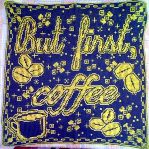 May include: A blue and yellow crocheted throw pillow with the text "But first, coffee" and a coffee cup and coffee beans.