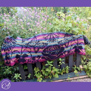 Peut inclure: Une couverture en crochet rectangulaire présentant une base en fil dégradé multicolore aux tons rose, violet, bleu et jaune, recouverte d'un motif mosaïque noir détaillé représentant divers motifs floraux et des silhouettes de roses.