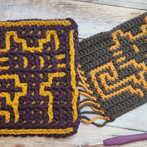 Puede incluir: Dos cuadrados tejidos a crochet con un patrón geométrico. Un cuadrado es morado y dorado, el otro es gris y dorado. Ambos cuadrados tienen flecos.