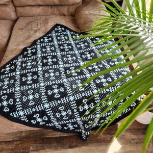 May include: A black and white crocheted throw blanket with a geometric pattern of stars and hearts. The blanket is made with a soft, textured yarn and has a light blue color.
