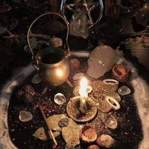K&ouml;nnte beinhalten: Eine mystische Szene mit einem kleinen Messingkessel, einer brennenden Kerze und einem Pentagramm. Klare Quarzkristalle, getrocknete Kr&auml;uter und andere rituelle Gegenst&auml;nde sind auf einer dunklen Oberfl&auml;che angeordnet, was eine spirituelle Atmosph&auml;re schafft.