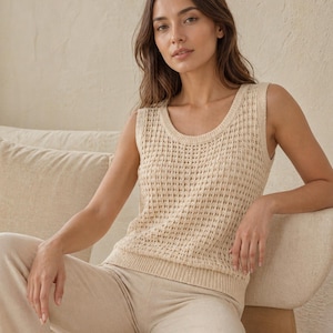 Puede incluir: Un top de punto sin mangas de color crema con cuello redondo. El top tiene un dise&ntilde;o de tejido abierto y texturizado. Combinado con pantalones beige a juego. El conjunto es de tonos neutros y parece estar hecho de un material suave y transpirable.