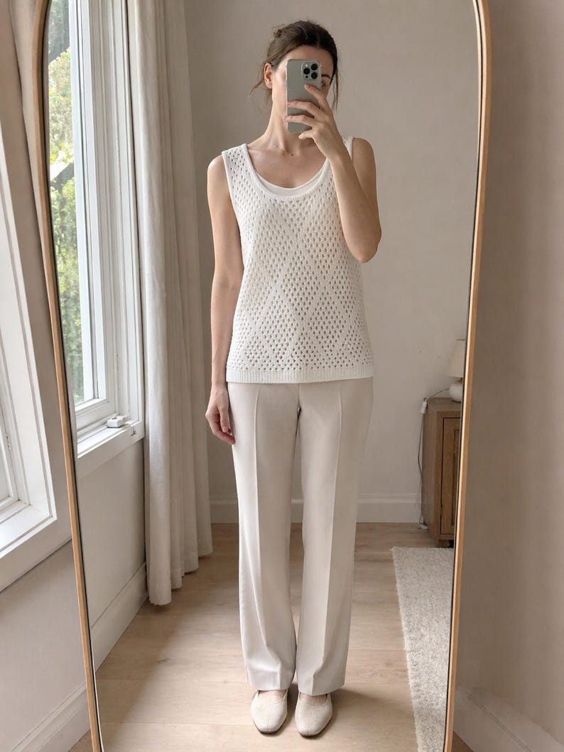 Puede incluir: Un top blanco sin mangas con una superposici&oacute;n de punto con estampado de diamantes, combinado con pantalones de pierna ancha de color beige claro. El conjunto incluye una camiseta interior con cuello redondo y zapatos beige a juego. El conjunto se captura en un espejo de cuerpo entero.