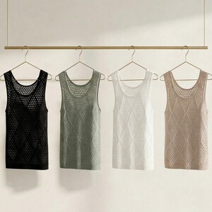 May include: Four tank tops in black, green, white, and beige hang on a gold rod. Each top has a scoop neck and a mesh-like knit design. The tops are displayed against a neutral background, showcasing the different colors and textures.
