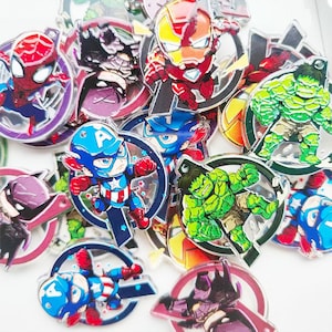 以下が含まれることがあります： カラフルなスーパーヒーローキャラクターのピンのコレクション。スパイダーマン、キャプテンアメリカ、アイアンマン、ハルクなどのキャラクターが登場します。各ピンは鮮やかな色で詳細なデザインで、円形の背景に配置されています。