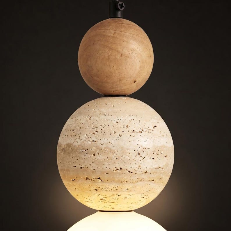May include: A modern pendant light fixture featuring three stacked spheres. The top sphere is made of light-colored wood, the middle sphere has a textured, beige stone appearance, and the bottom sphere is a glowing white. The fixture hangs from a black metal rod.