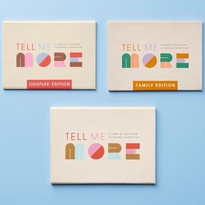 Könnte beinhalten: Drei rechteckige Spielschachteln mit dem Titel Tell Me More, ein Fragespiel zur Vertiefung von Verbindungen. Eine Schachtel ist mit Couples' Edition in rotem, rosa und braunem Text beschriftet. Eine weitere mit Family Edition in Grün und Orange.