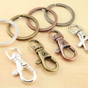 May include: Assortment of key rings and swivel clasps in silver, bronze, and copper finishes. The key rings are round and the swivel clasps are hook-shaped.