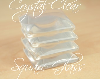 Puede incluir: Una pila de cuatro baldosas de vidrio cuadradas y transparentes. Las baldosas están apiladas una encima de la otra, con un ligero espacio entre cada una. El texto "Crystal Clear Square Glass" está escrito en cursiva.