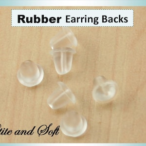 May include: Five clear rubber earring backs, described as "Petite and Soft", on a light wood surface. Rubber Earring Backs.
