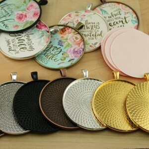 May include: Assortment of round metal trays with a decorative swirl pattern. The trays are in various finishes, including silver, gold, black, and copper. The trays are designed to hold round glass or plastic cabochons for jewelry making.