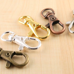 May include: Four metal swivel clasps in different finishes: gold, silver, antique brass, and copper. These clasps are great for attaching to keychains, bags, or other accessories.