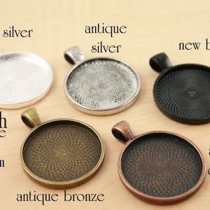 May include: Five 1-inch round metal pendant trays with different finishes: shiny silver, antique silver, new black, antique bronze, and antique copper. Each tray has a 25mm inside diameter.