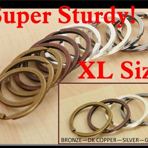 May include: A set of four large, split key rings in bronze, dark copper, silver, and gunmetal finishes. The rings are labelled "BRONZE - DK COPPER - SILVER - GUN M". The text "Super Sturdy! XL Size" is displayed above the rings.