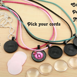 May include: Complete Pendant Making Kit with 1 inch black trays, pink cords, teal cords, black cords, and a silver chain.  The kit includes four round glass cabochons, four round black metal pendant bases, and one round pendant base with a pink and white flower design and the letter "b".  Pick your cords text is visible in the image.