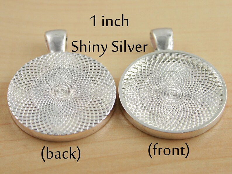 May include: A 1 inch shiny silver round pendant with a textured back and a smooth front. The pendant is for crafting and jewellery making.