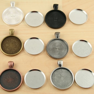 May include: Twelve round, silver-toned metal pendant trays with a decorative pattern. Six trays have a clear glass insert, and six trays have a silver-toned metal insert.