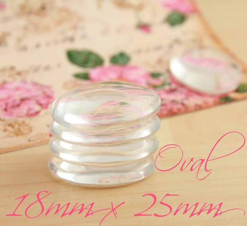 May include: Stack of four iridescent oval glass cabochons, measuring 18mm x 25mm. The cabochons are stacked on a light wood surface.