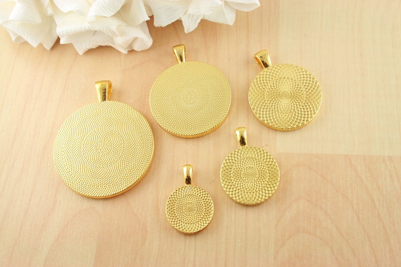May include: Five gold-colored metal pendant trays of different sizes. The trays are round and have a textured surface. They are all facing the camera.