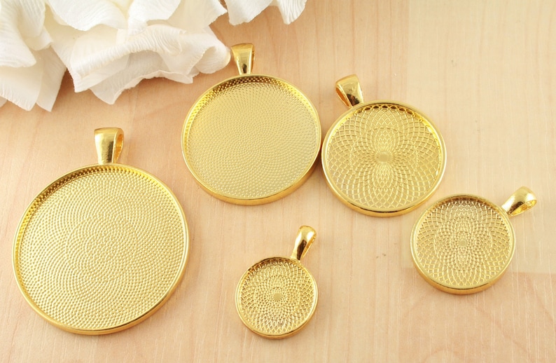 May include: Five gold-toned metal pendant trays of different sizes. The trays have a circular shape and a textured surface.