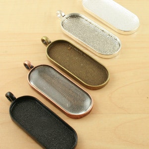 May include: Five oval-shaped pendant trays in different finishes: silver, black, copper, bronze, and clear glass. Each tray has a textured surface and a loop at the top for hanging.