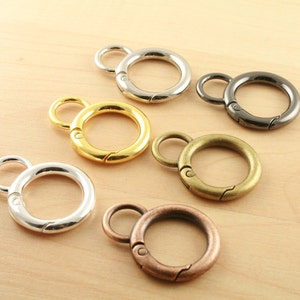 May include: Five different metal key rings with a swivel clasp. The key rings are silver, gold, bronze, black, and a lighter shade of silver.