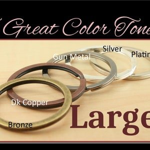 May include: Five large key rings in different metal finishes: bronze, dark copper, gun metal, silver, and platinum. The key rings are arranged in a row on a light wood surface. The text "Large" is written in large, dark red letters below the key rings.