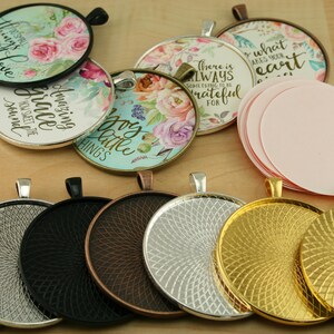 May include: Assortment of round metal pendant trays with a variety of finishes, including silver, black, copper, and gold. The trays have a decorative swirl pattern and are ready to be used for crafting projects.  Some of the trays have pre-made designs with floral patterns and inspirational quotes, such as "Amazing Grace" and "There is always something to be grateful for".