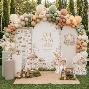 Pode incluir: Um cenário de chá de bebê com um painel arqueado com o texto OH BABY A Little Love is Sprouting, rodeado por uma guirlanda de balões em creme, verde sálvia e pêssego, com recortes de cogumelos, um cervo e pedestais cilíndricos.