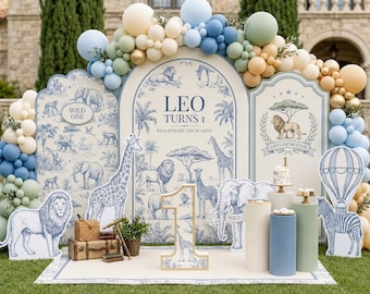 May include: A birthday party backdrop featuring three arched panels with blue and white safari animal illustrations, text reading LEO TURNS 1, and a large number 1 cutout. The display is decorated with a balloon arch in blue, green, and beige.