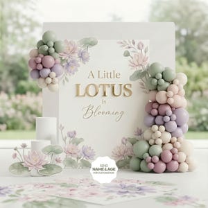 May include: A white sign with the text "A Little Lotus is Blooming" in gold lettering, surrounded by floral and balloon decorations in pastel colors. The sign is decorated with lotus flowers and leaves.