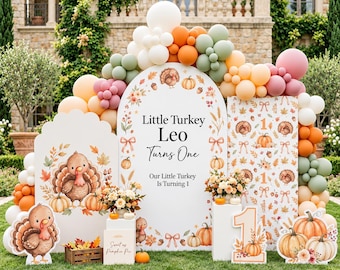 May include: A decorative party backdrop set featuring an arched sign with the text Little Turkey Leo Turns One, Our Little Turkey Is Turning 1, accompanied by turkey and pumpkin illustrations, surrounded by a balloon arch and cutouts.