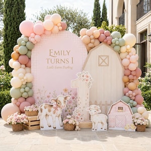 Puede incluir: Un fondo de fiesta con un letrero arqueado rosa con el texto Emily Turns 1 Little Farm Darling, un recorte de granero de madera y un número uno grande. La decoración incluye una guirnalda de globos en tonos rosa, melocotón y verde salvia, junto con figuras de un ternero, un cordero y un granero pequeño, con cestas de flores.