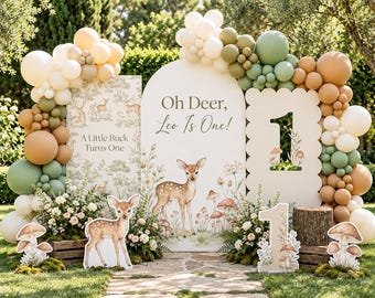 May include: A birthday party display featuring an arched backdrop with the text Oh Deer, Leo Is One!, a rectangular sign reading A Little Buck Turns One, and a scalloped sign with the number 1. Decorations include deer illustrations, mushroom cutouts, and a balloon garland in shades of cream, sage green, and tan.