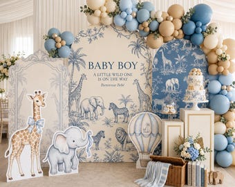 May include: A baby shower display featuring two arched backdrops with blue and beige jungle animal illustrations, text reading BABY BOY A LITTLE WILD ONE IS ON THE WAY, a balloon arch, a tiered cake, a wicker basket, and cutout giraffe and elephant.