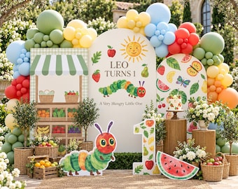 May include: A party backdrop display featuring a large arch with the text Leo Turns 1 and A Very Hungry Little One, a green caterpillar illustration, a sun, and fruit. Includes balloon garlands in green, yellow, blue, red, and orange colors.